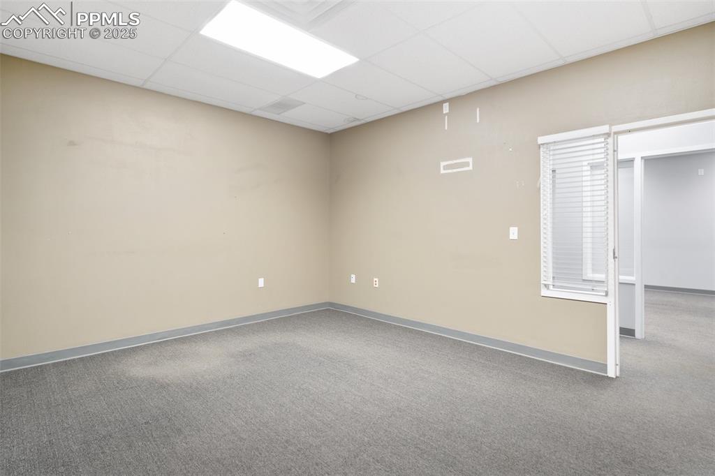 Image 17 of 26: Carpeted empty room featuring a drop ceiling and baseboards