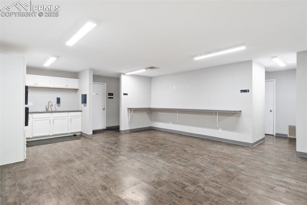 Image 19 of 26: Unfurnished living room featuring dark wood-style floors and a sink