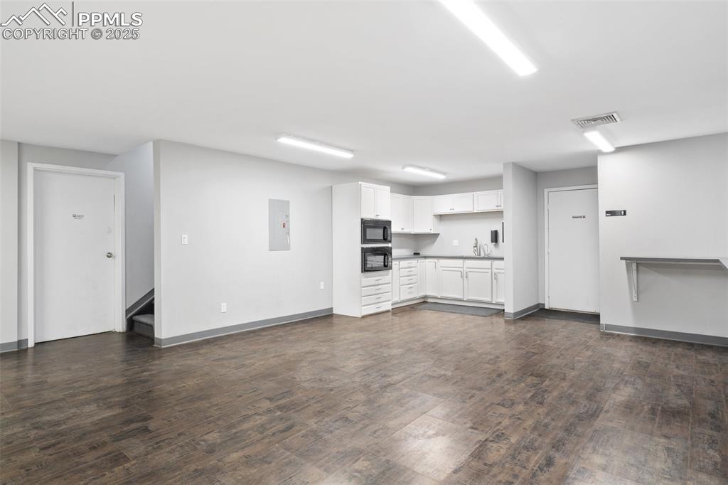 Image 21 of 26: Unfurnished living room featuring electric panel, dark wood finished floors