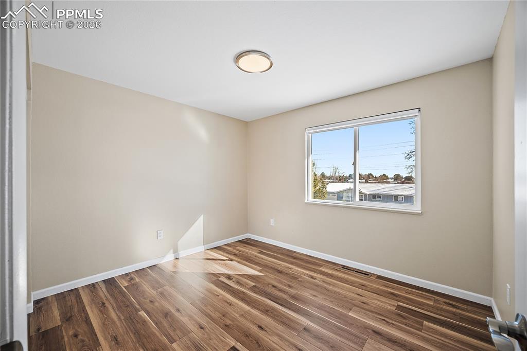 Image 22 of 45: Upstairs bedroom 2 new flooring, paint and lighting. 