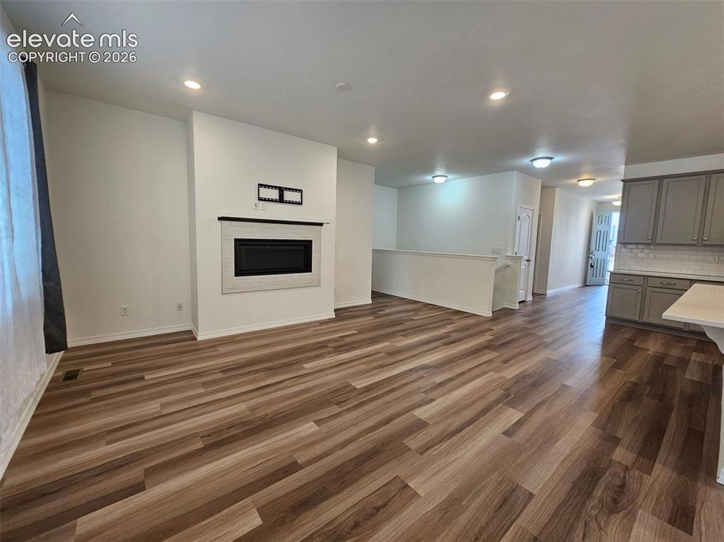 Image 11 of 25: Wood-finish flooring throughout, recessed lighting, and a modern fireplace
