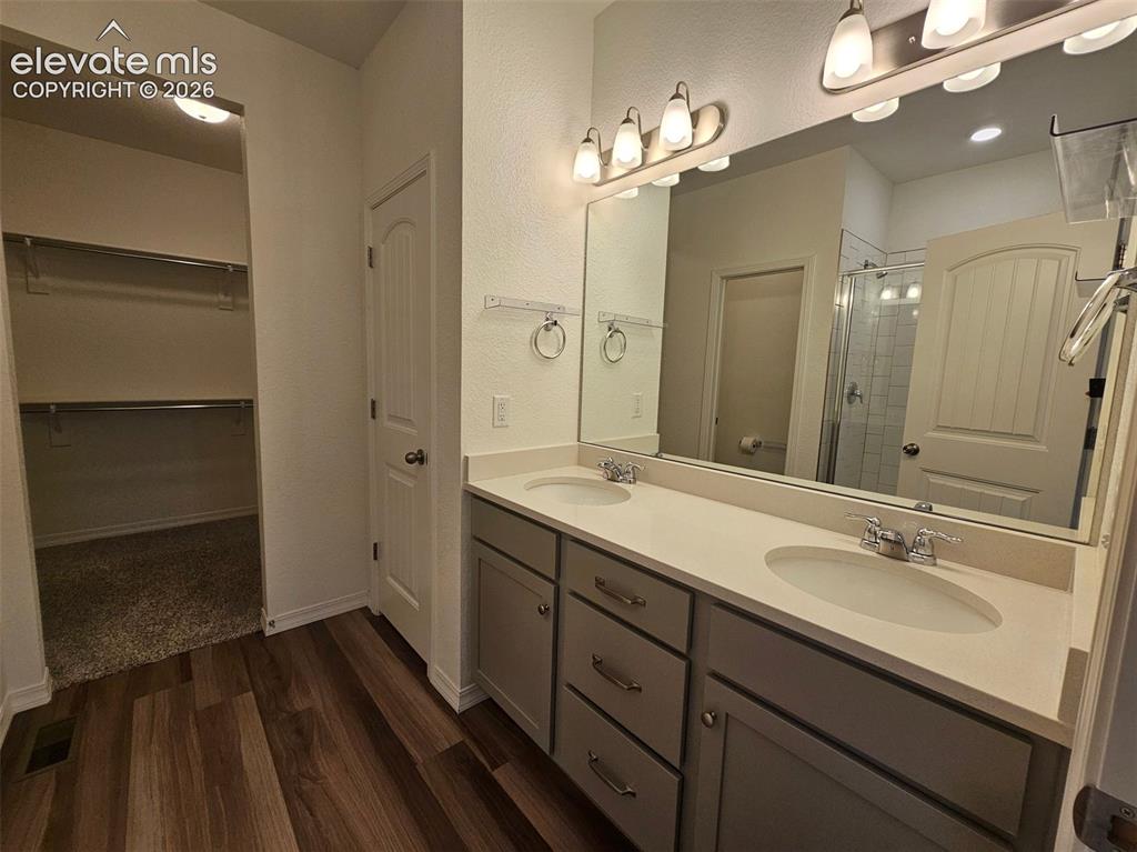 Image 15 of 25: Dual vanity with integrated sinks, wood-finish flooring, ample storage cabi
