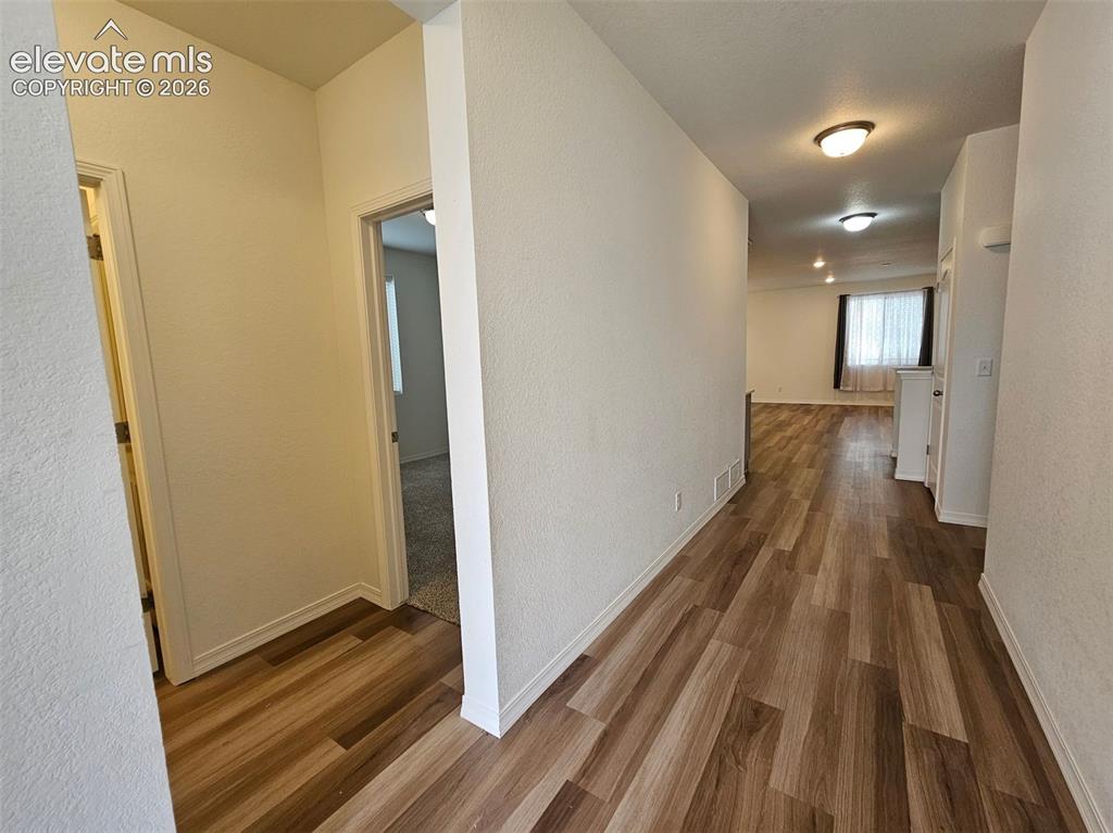 Image 2 of 25: Wood-finish flooring throughout the hallway and living area