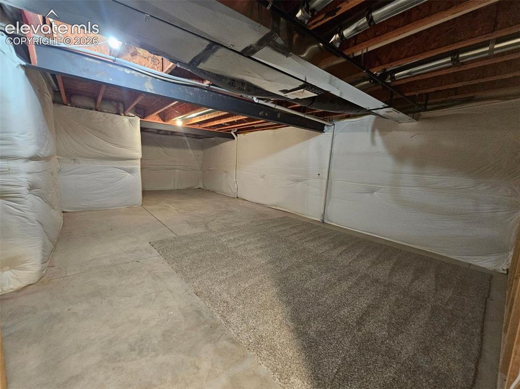 Image 23 of 25: Unfinished basement space with exposed structural elements and concrete flo