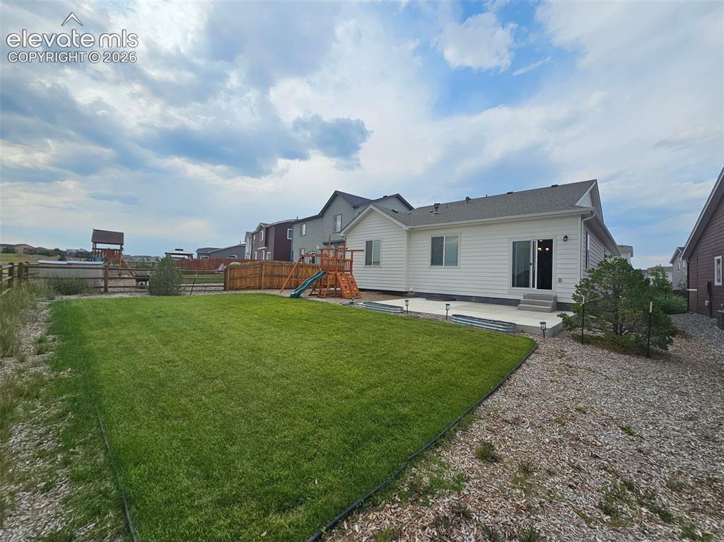 Image 24 of 25: Expansive backyard featuring a manicured lawn, concrete patio, and mature l