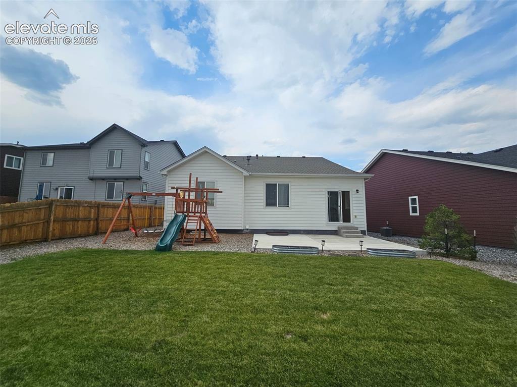 Image 25 of 25: Expansive backyard with a manicured lawn, full privacy fencing, concrete pa