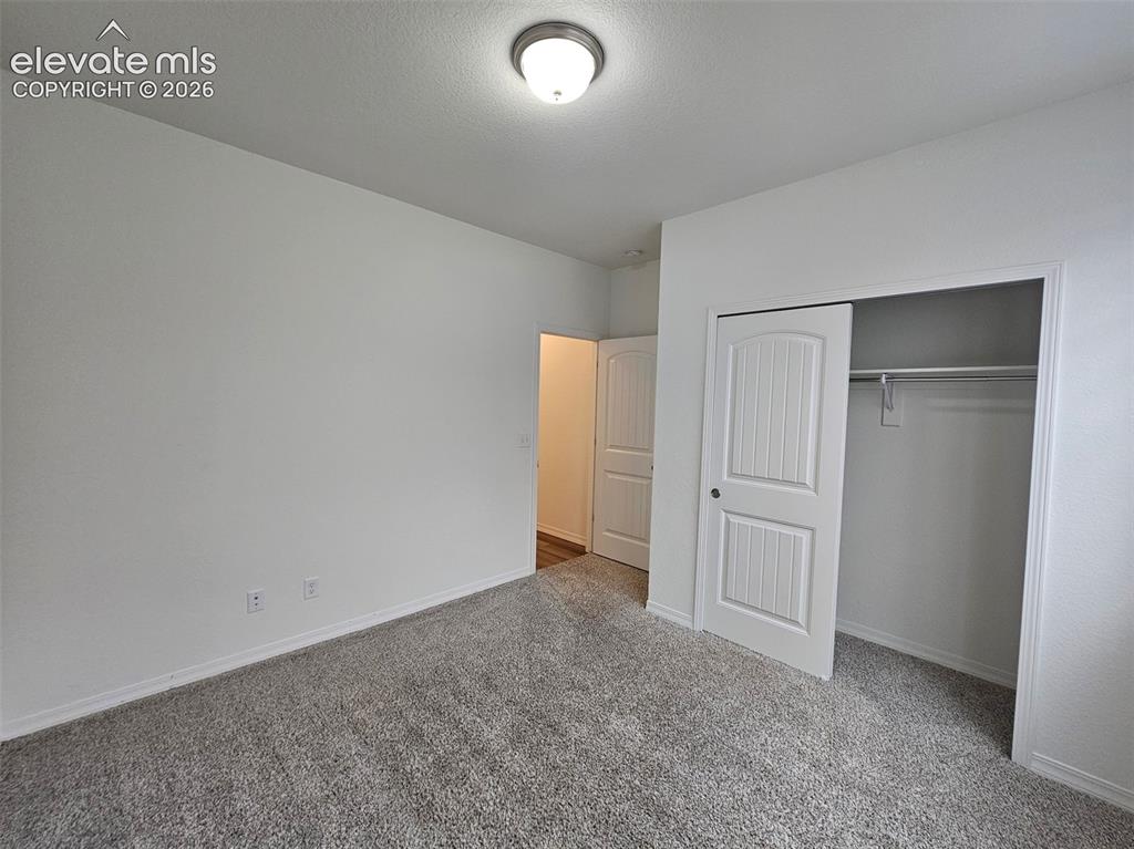 Image 4 of 25: Light gray carpeting, white painted walls, a flush-mount ceiling light fixt