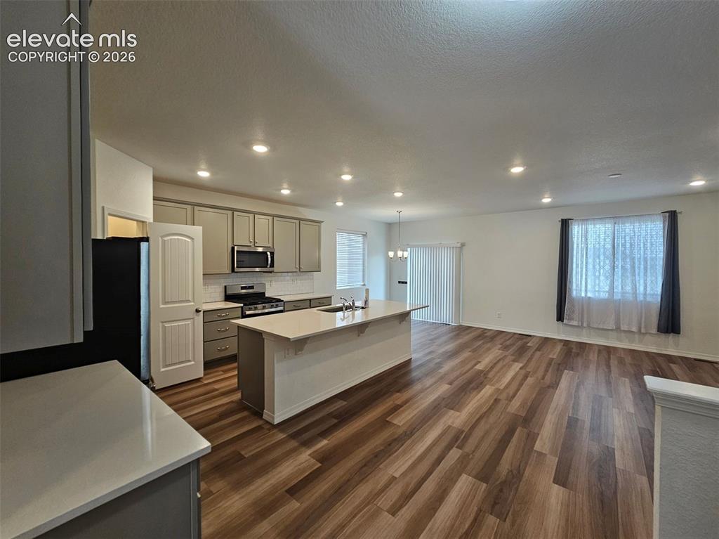 Image 9 of 25: Open-concept kitchen and living area featuring wood-finish flooring, recess