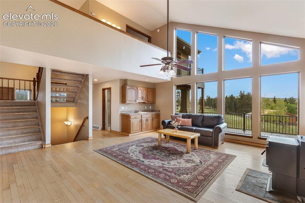 Image 8 of 50: Two-story living area featuring wood-finish flooring, a wood-burning stove 