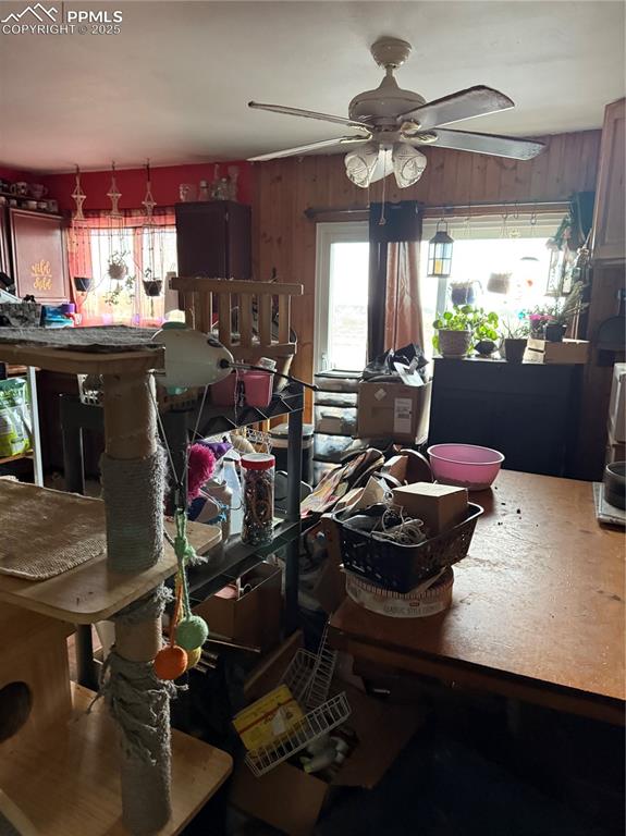 Image 3 of 10: Dining space with ceiling fan and wooden walls
