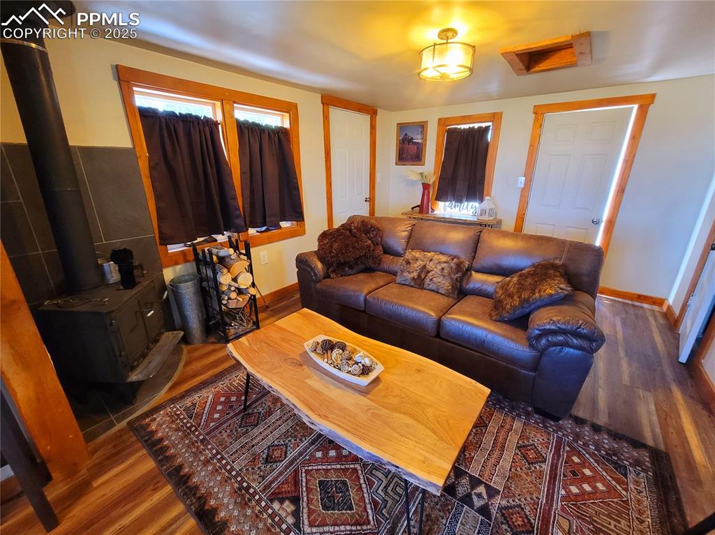 Image 10 of 22: Living room with a wood stove and wood finished floors