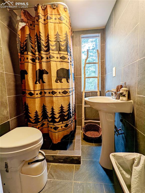 Image 20 of 22: Bathroom with tile walls and a shower with curtain