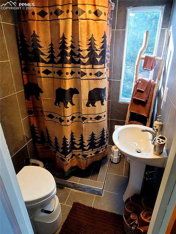 Image 21 of 22: Bathroom with tile patterned flooring, tile walls, a shower with curtain, a