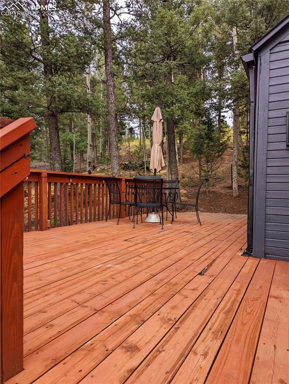 Image 4 of 22: Wooden deck with outdoor dining area and view of wooded area