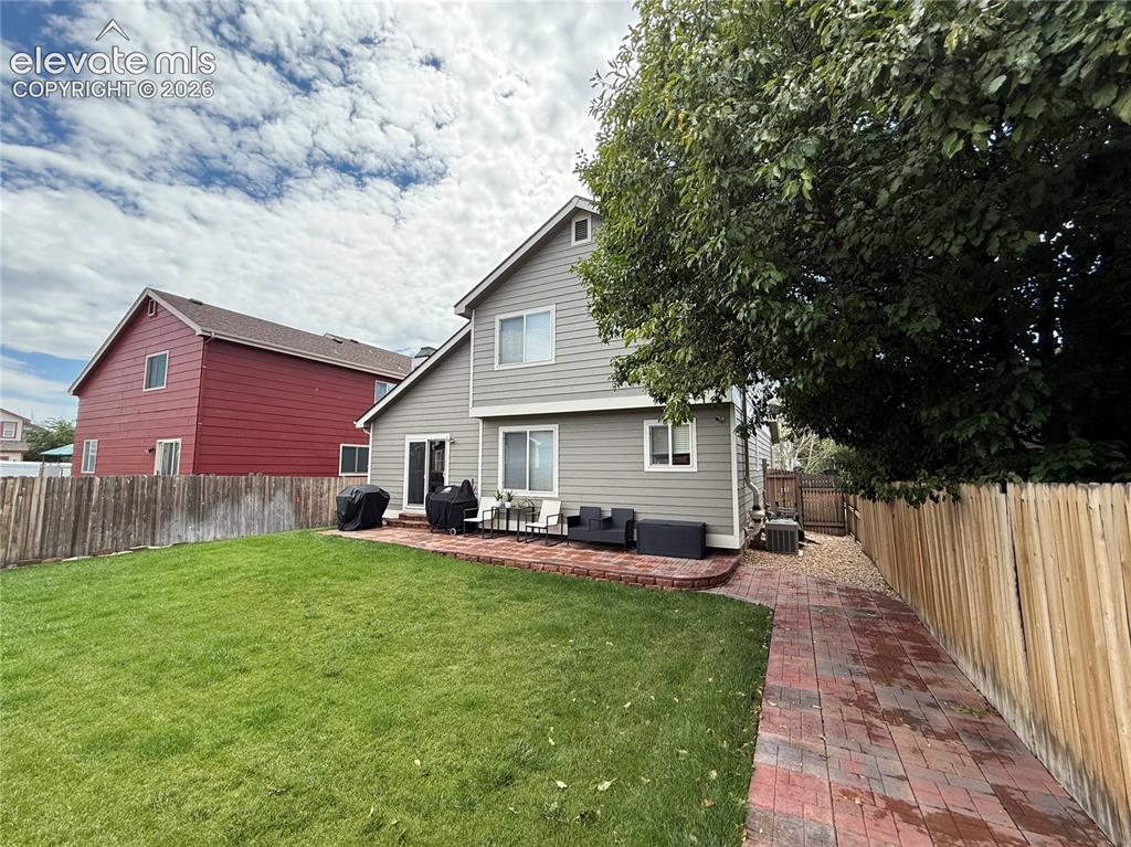 Image 15 of 15: Expansive backyard featuring a manicured lawn, brick paver patio, and full 
