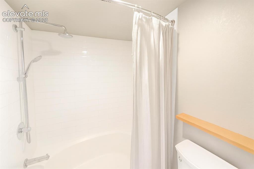 Image 9 of 15: Bathtub with white subway tile surround, chrome fixtures, and a wall-mounte