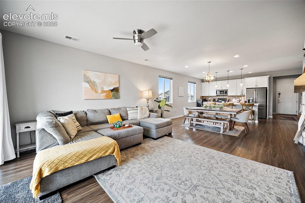 Image 11 of 38: Open-concept living space with wood-finish flooring, recessed lighting, and