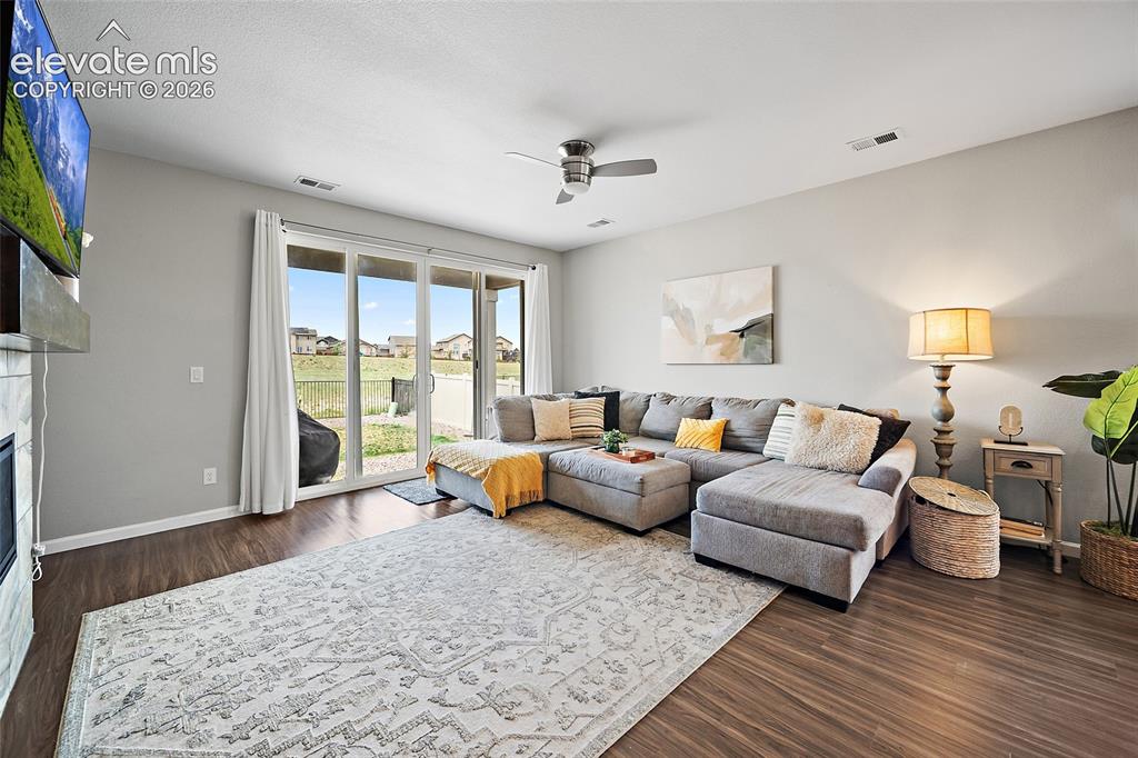 Image 12 of 38: Spacious living area featuring wood-finish flooring, a ceiling fan, and sli