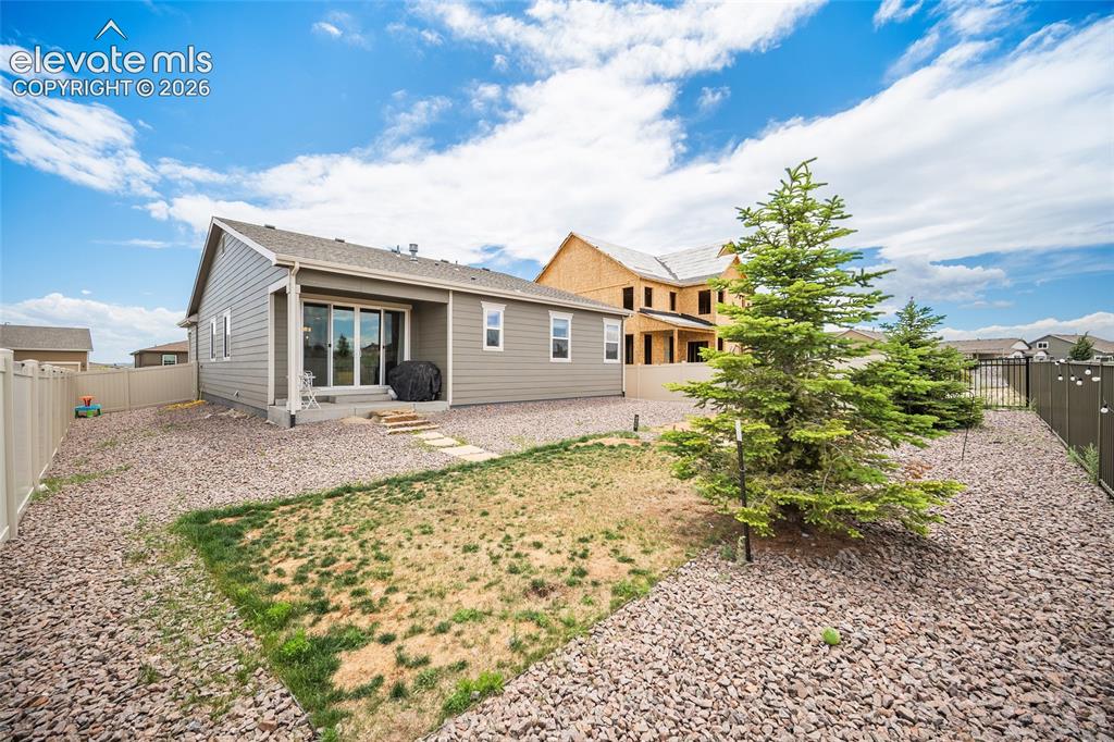 Image 26 of 38: Rear exterior featuring gray siding, a covered patio, and sliding glass doo