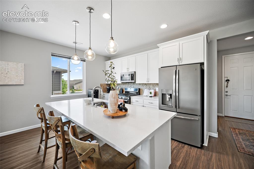 Image 3 of 38: Modern kitchen featuring white cabinetry, a large white island with seating