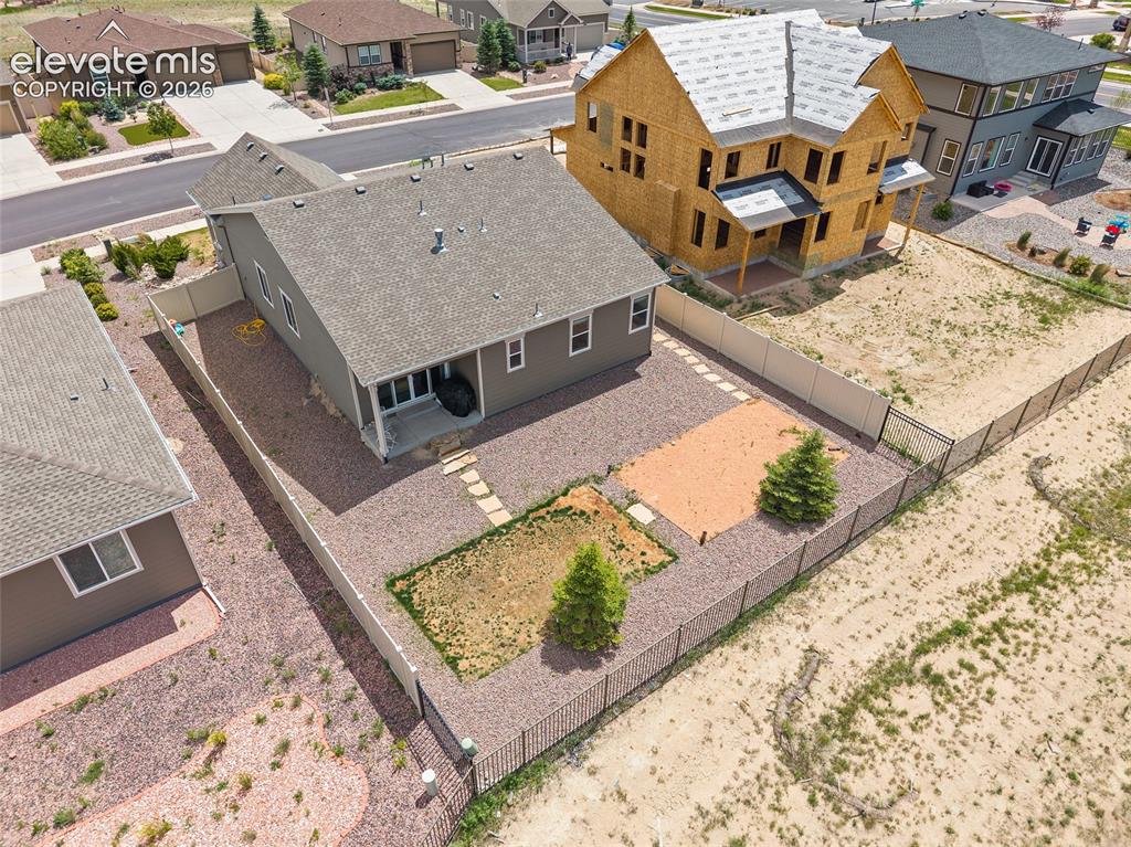 Image 34 of 38: Rear exterior of a single-story residence featuring a covered patio, gravel