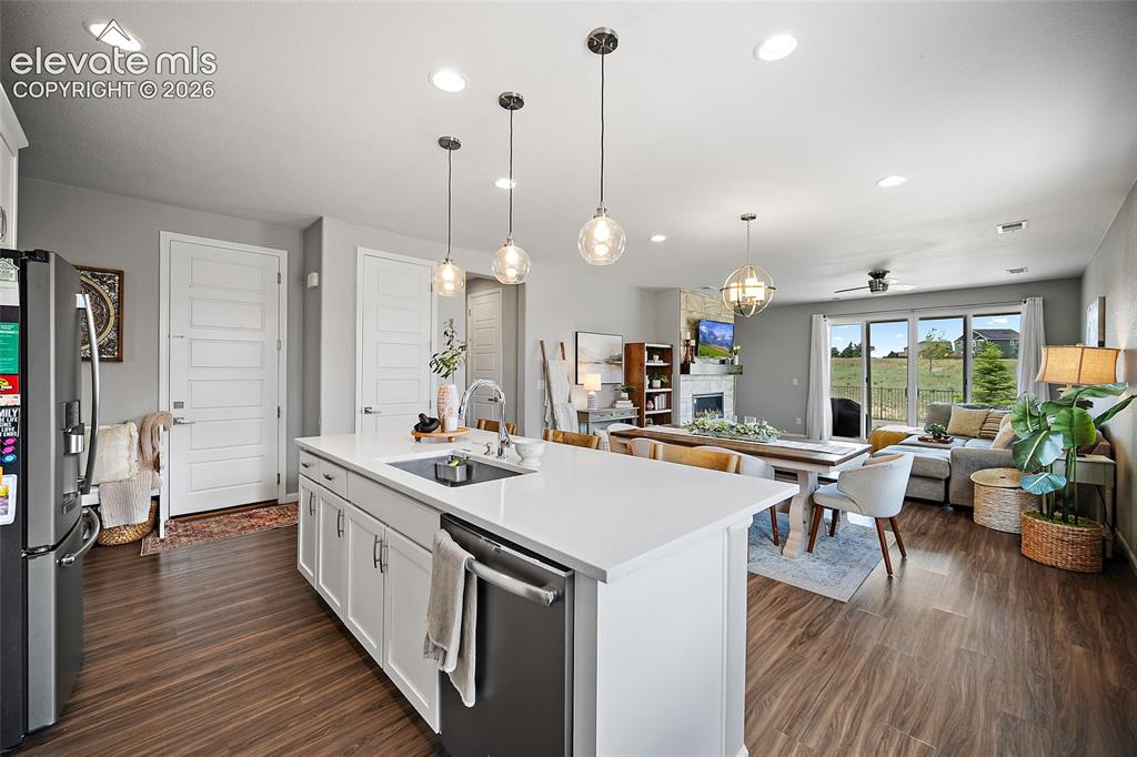 Image 4 of 38: Kitchen island with a white countertop and integrated sink, pendant lightin