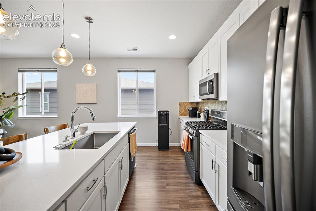 Image 7 of 38: Modern kitchen featuring a large island with an undermount sink, white cabi