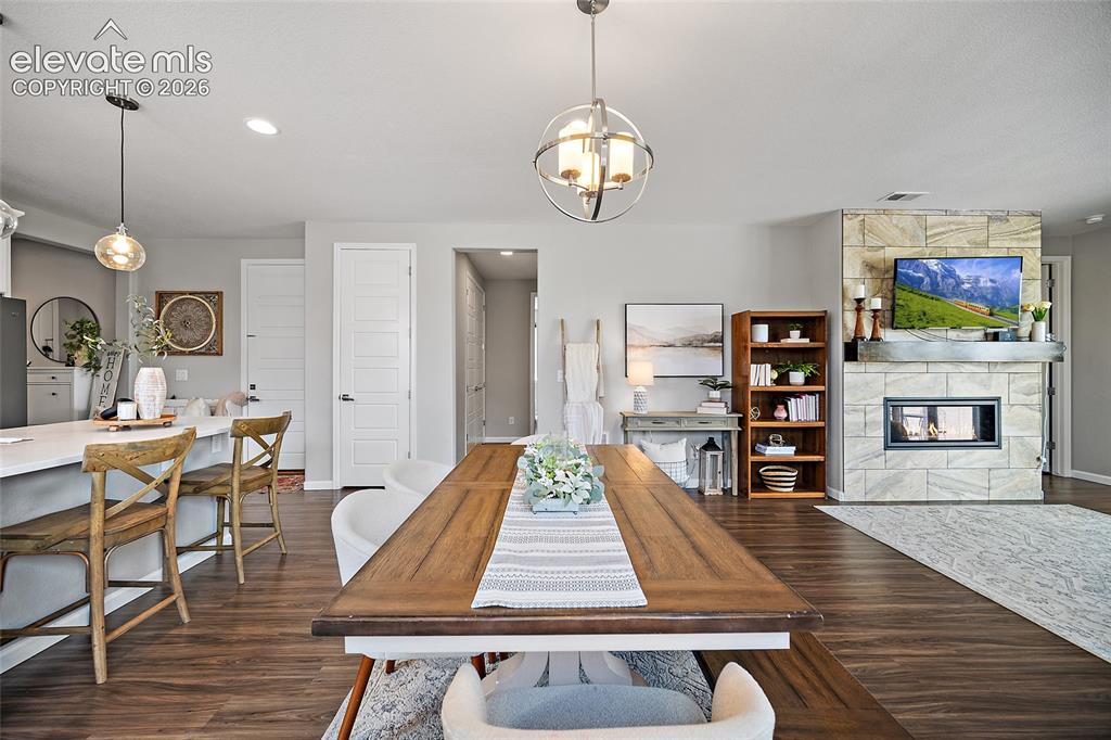 Image 8 of 38: Open-concept living area with wood-finish flooring, a stone-faced fireplace
