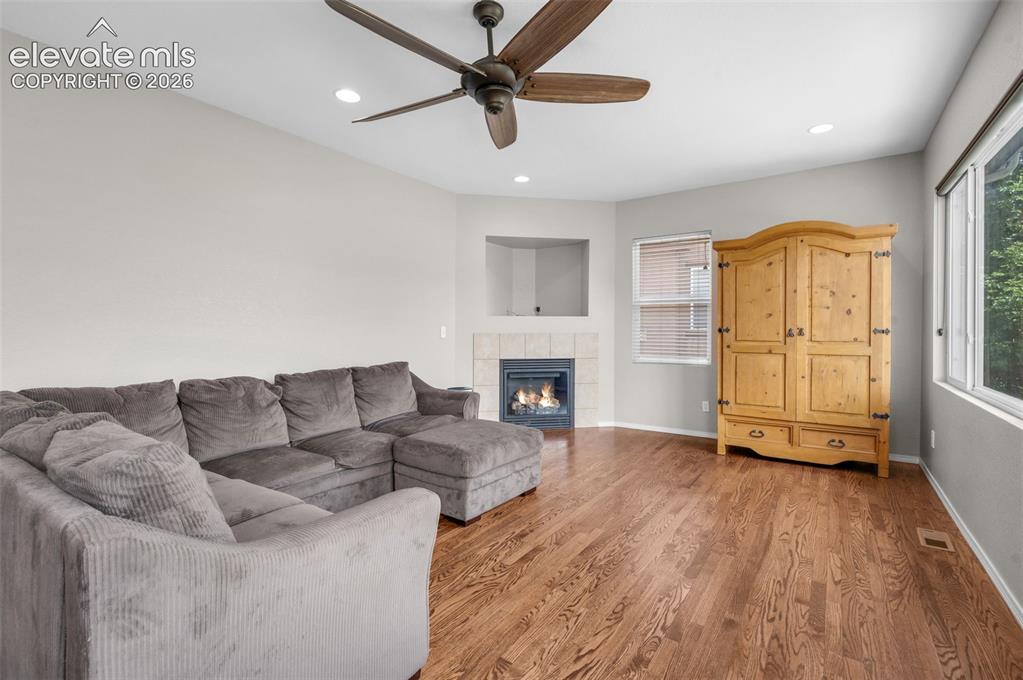 Image 10 of 34: Spacious living area featuring wood-finish flooring, a corner gas fireplace