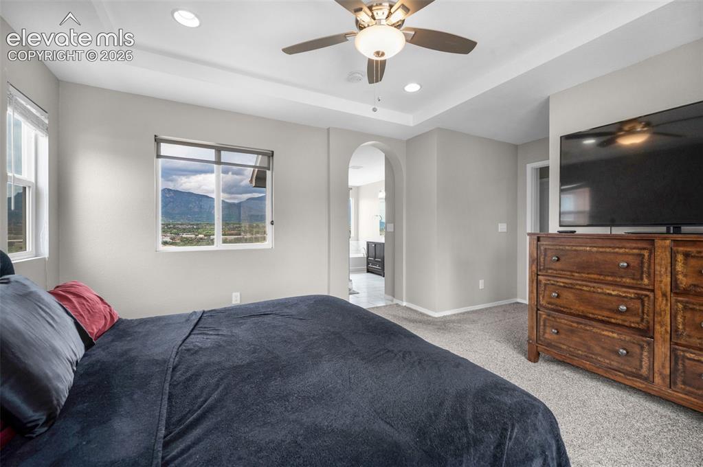Image 15 of 34: Tray ceiling with recessed lighting and ceiling fan. The primary bath doorw