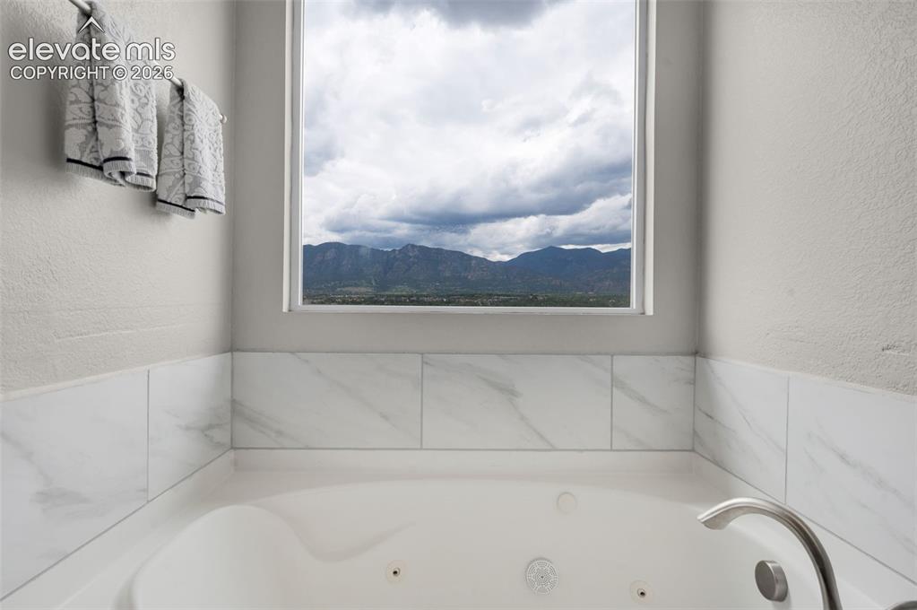 Image 17 of 34: Built-in jetted tub with a mountain view, tile surround, and brushed metal