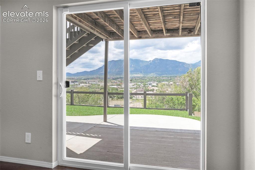 Image 23 of 34: Sliding glass doors opening to an outdoor patio with mountain scenery and a
