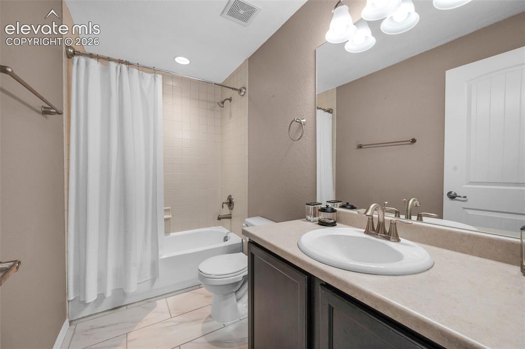 Image 26 of 34: Full bathroom featuring a white bathtub with subway tile surround, brushed