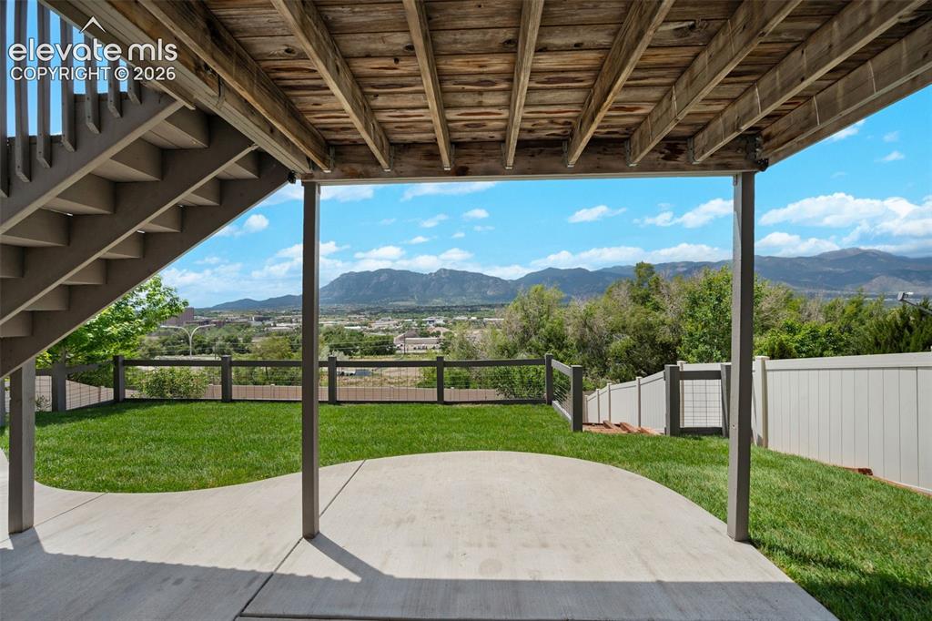 Image 27 of 34: Expansive concrete patio under an elevated deck with exposed wood joists