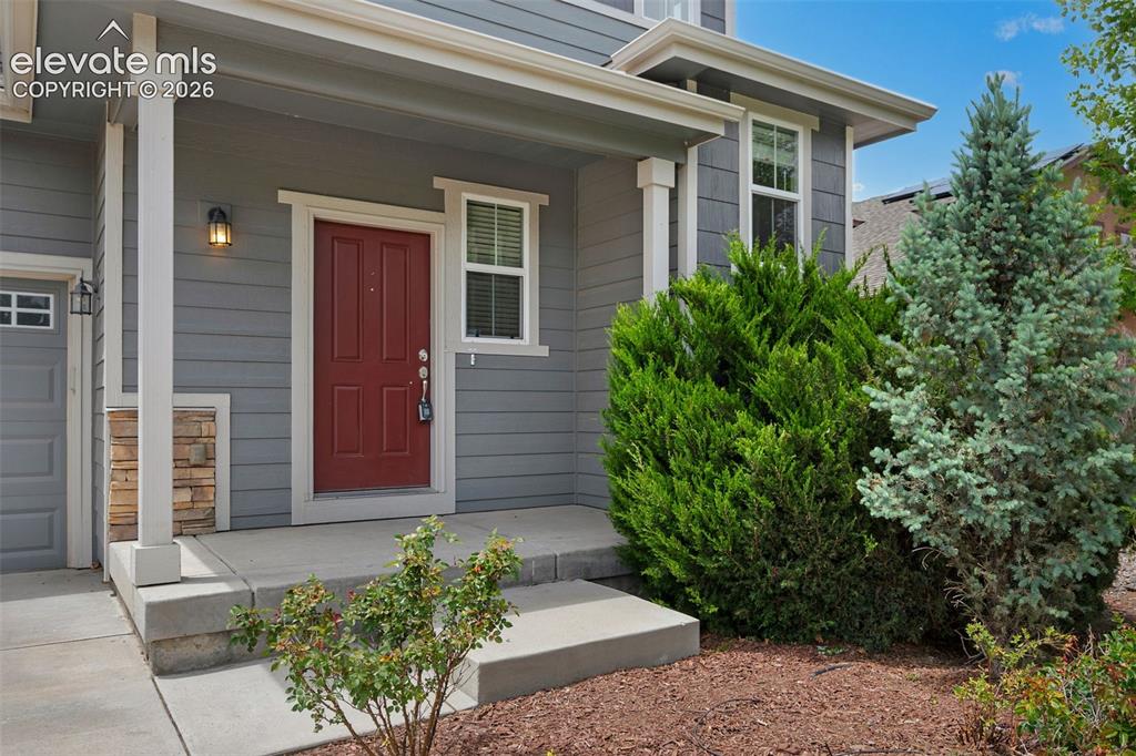 Image 3 of 34: Inviting front entry featuring a red paneled door, gray siding, white trim,