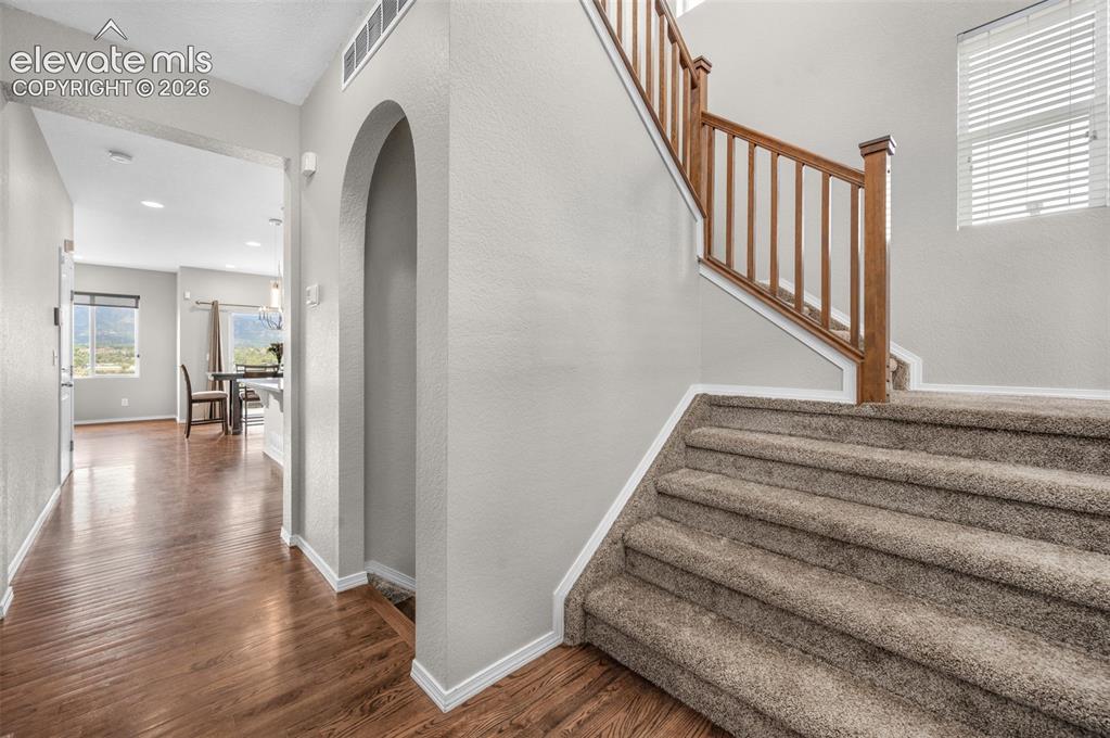 Image 4 of 34: Carpeted staircase with wood banister and white risers