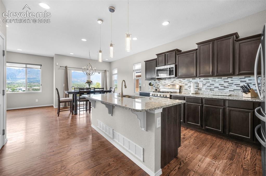 Image 5 of 34: Open-concept kitchen featuring wood-finish flooring, dark wood cabinetry, a