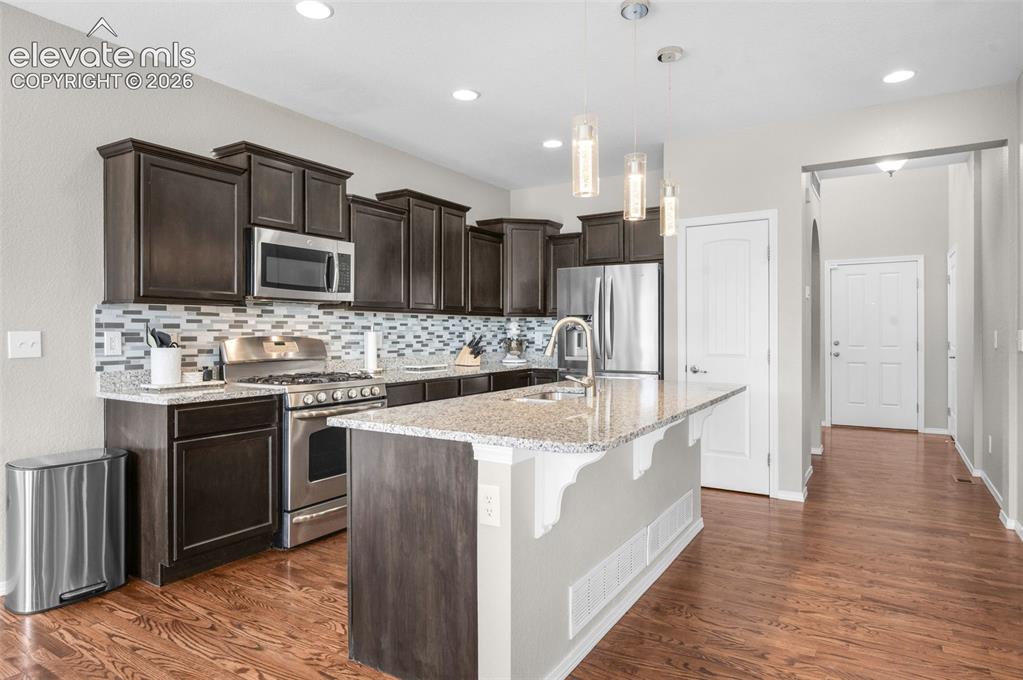 Image 6 of 34: Kitchen featuring dark wood-finish cabinetry, stainless steel appliances, a