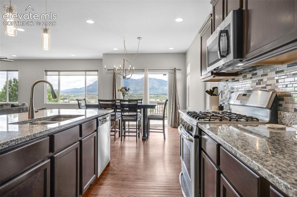 Image 7 of 34: Modern kitchen featuring dark wood cabinetry, stainless steel appliances, g
