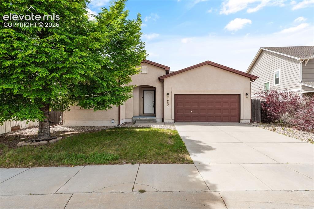 Caption: Single-story stucco exterior featuring an arched entryway, attached two-car garage, concrete drivewa