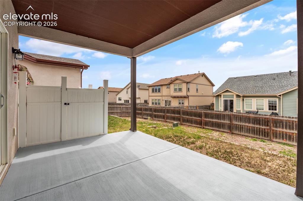 Image 11 of 20: Covered concrete patio featuring an exterior wall-mounted light fixture, a