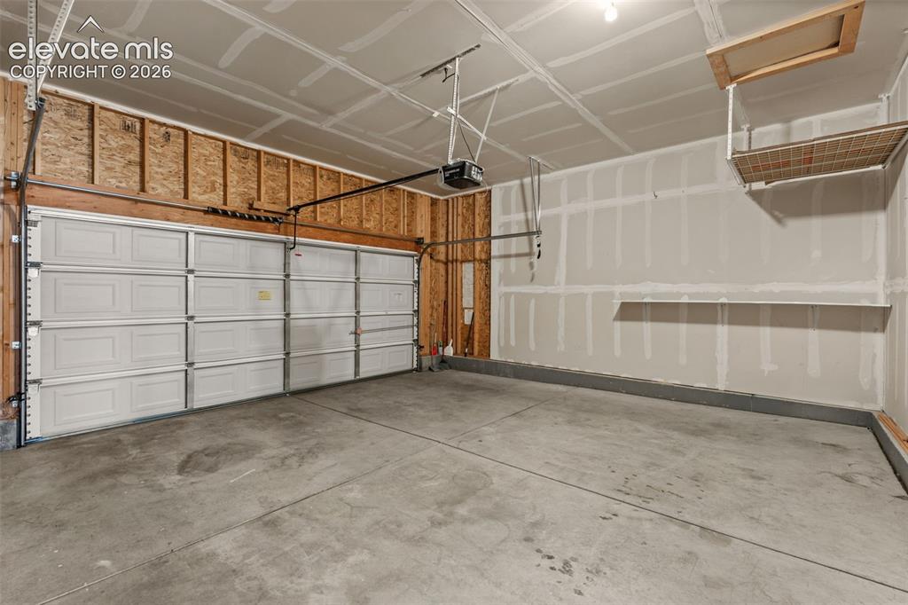 Image 16 of 20: Multi-car garage featuring a sectional overhead door, concrete flooring, bu