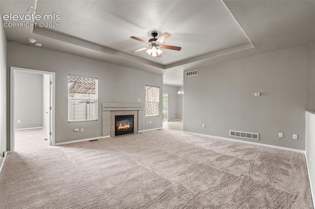 Image 3 of 20: Tray ceiling featuring a central ceiling fan with integrated lighting, a fi