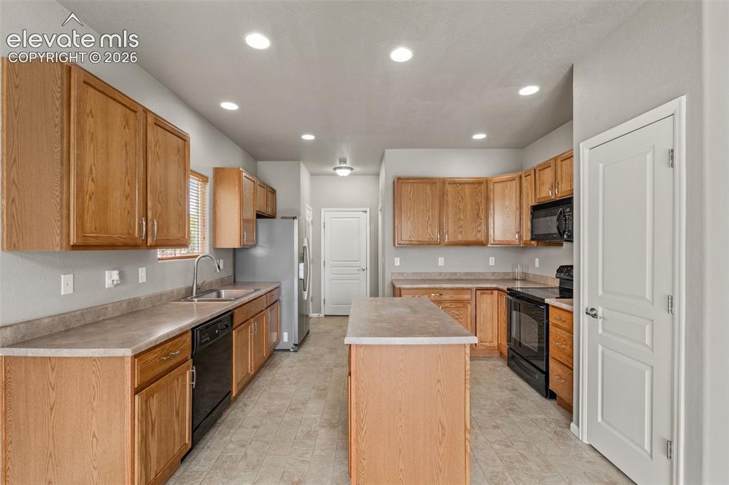 Image 5 of 20: Kitchen featuring natural wood cabinetry, a center island, recessed ceiling