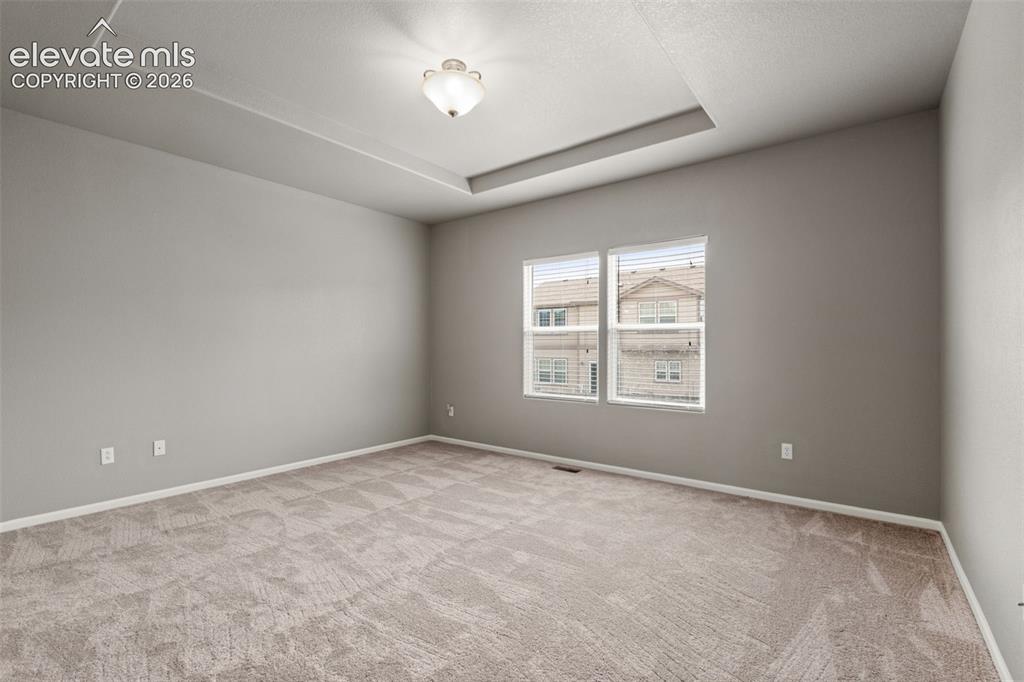 Image 6 of 20: Tray ceiling, neutral wall color, plush wall-to-wall carpeting, and dual wi