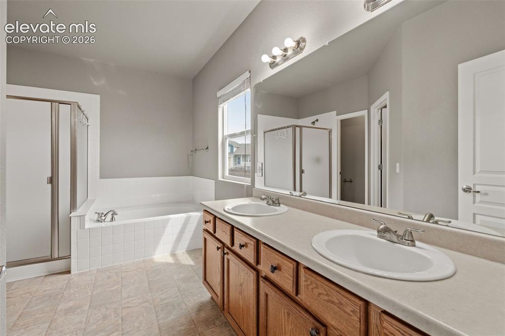 Image 7 of 20: Bathroom featuring a dual-sink vanity with wood cabinetry, a tiled-surround
