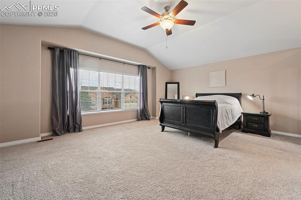 Image 23 of 44: Primary bedroom with lofted ceiling, bay window, and elegant finishes