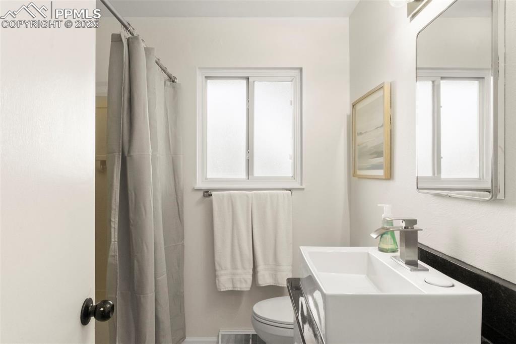 Image 15 of 30: Full bathroom with a shower with shower curtain and vanity