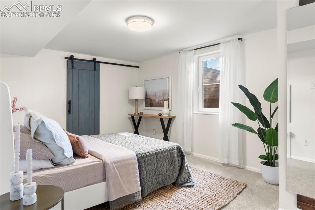 Image 20 of 30: Bedroom featuring a barn door and carpet flooring