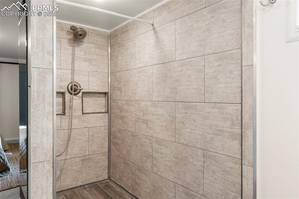 Image 22 of 30: Bathroom featuring a tile shower and dark wood-type flooring